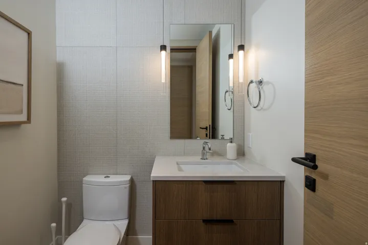 Modern vanity with a light wood-finish and integrated sink, complemented by a stone-finish countertop