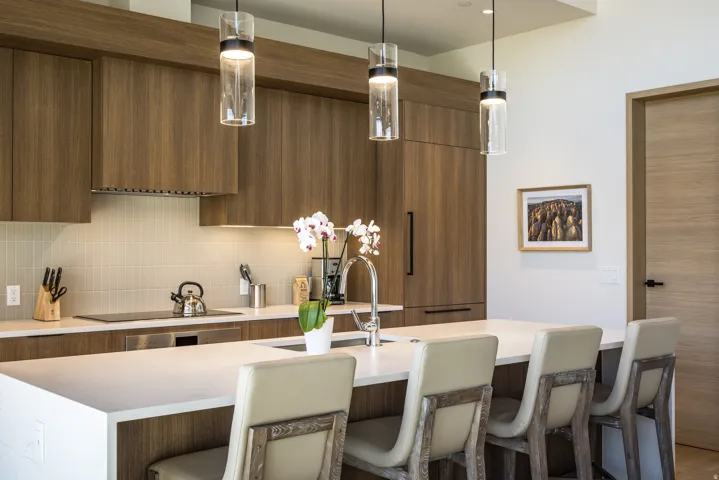 Contemporary kitchen featuring wood-grain cabinetry, a large center island with seating, a smooth cooktop, and a tile backsplash