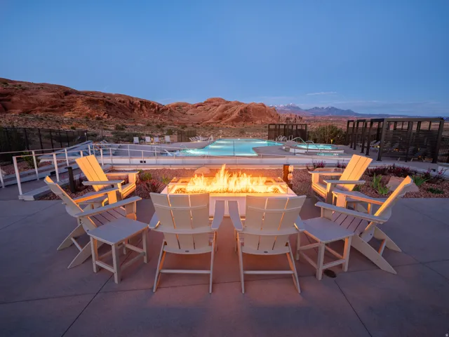 Outdoor fire pit surrounded by Adirondack-style chairs on a concrete patio