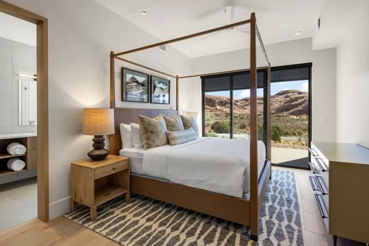 Spacious bedroom featuring large format windows, recessed lighting, wood-finish flooring, and direct access to an attached bathroom with a built-in vanity and wall-mounted mirror
