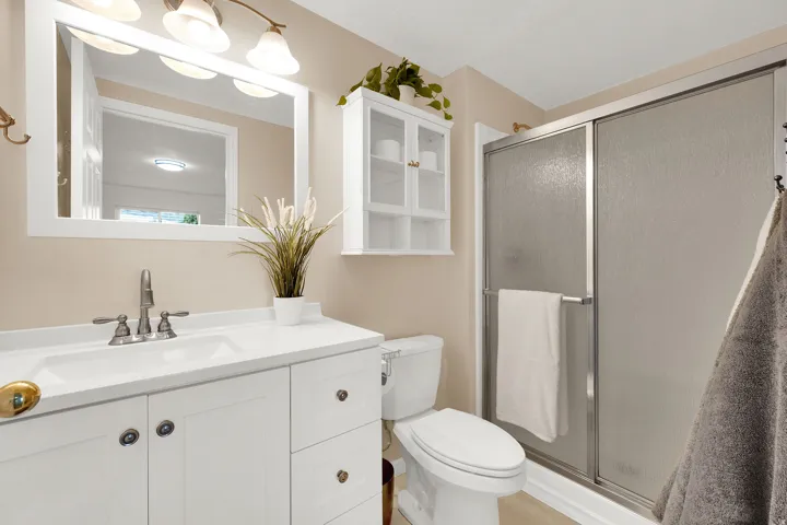 White vanity with a built-in sink, brushed nickel faucet, and a large framed mirror