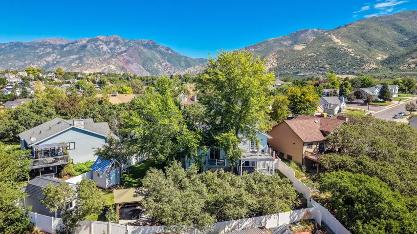 Mountain backdrop, lush trees, blue skies, residential neighborhood, private fencing