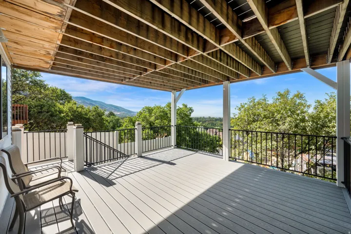 Spacious covered deck featuring composite decking and black metal railings