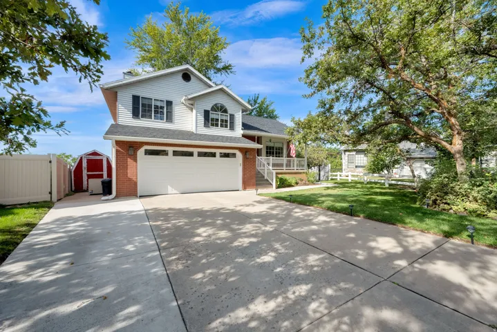 Two-story exterior with brick and siding facade, attached two-car garage, and mature trees