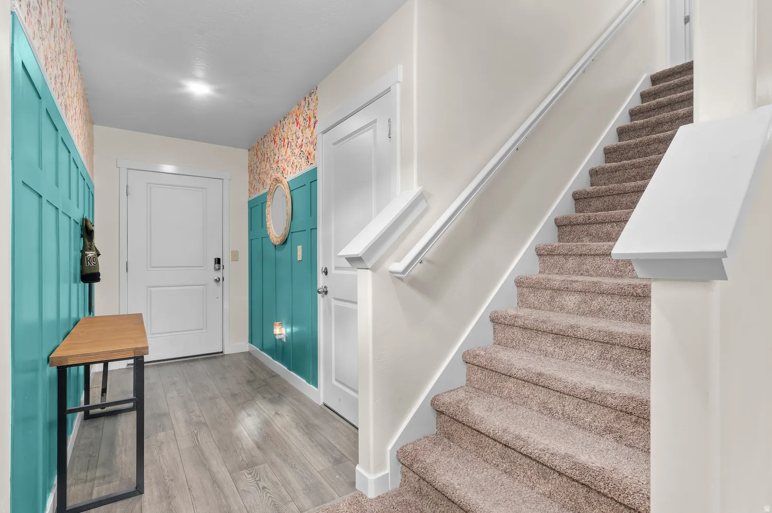 Hard-surface flooring, carpeted staircase, paneled accent walls, interior doors, and overhead lighting