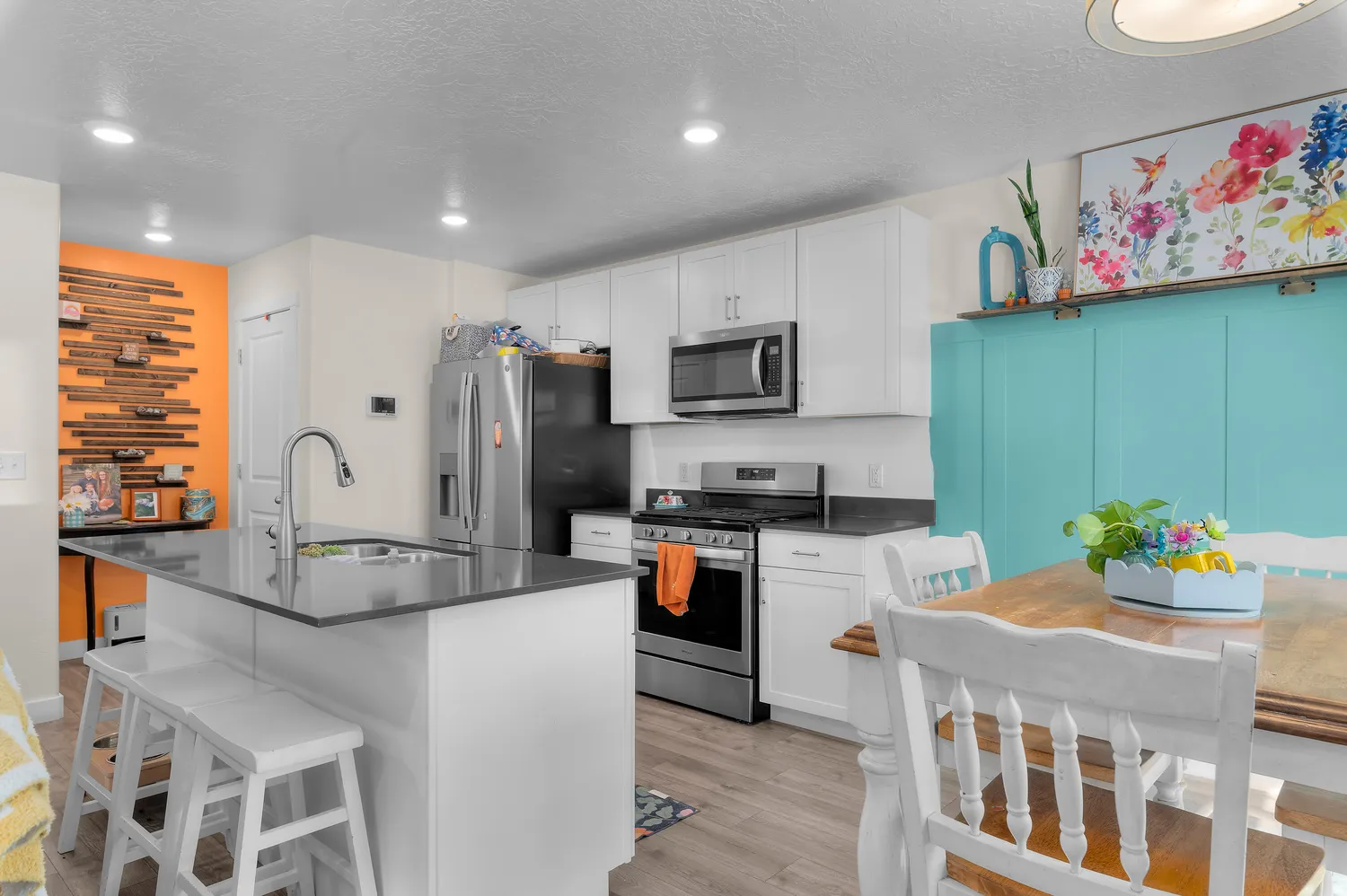 Kitchen featuring an island with a sink, white cabinetry, stainless steel appliances, recessed lighting, and wood-finish flooring