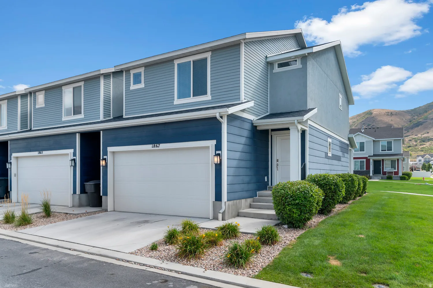 Two-story exterior with multi-toned siding, attached garage, concrete driveway, and front entry stairs