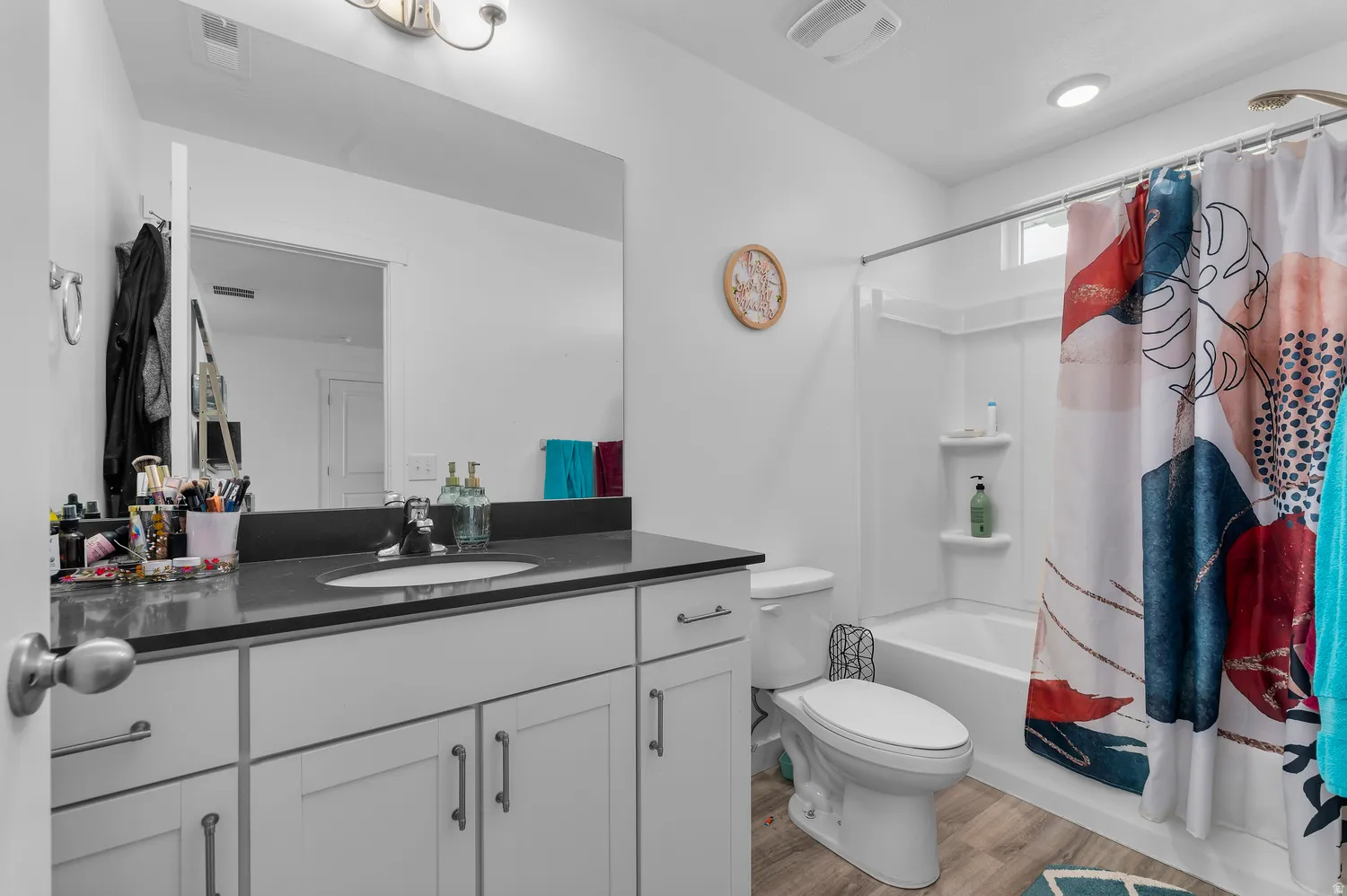 White vanity with shaker-style cabinetry, a dark countertop, and an undermount sink