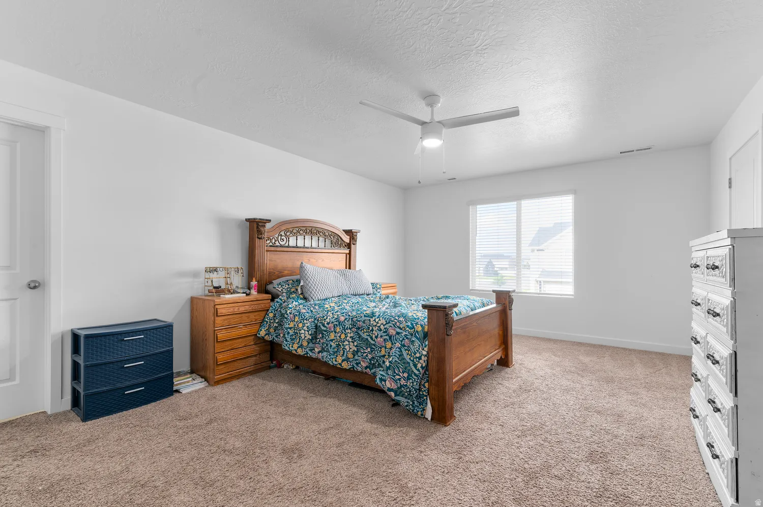 Carpeted flooring, white walls, ceiling fan with light, and a window with blinds