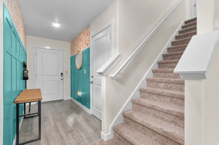 Hard-surface flooring, carpeted staircase, paneled accent walls, interior doors, and overhead lighting