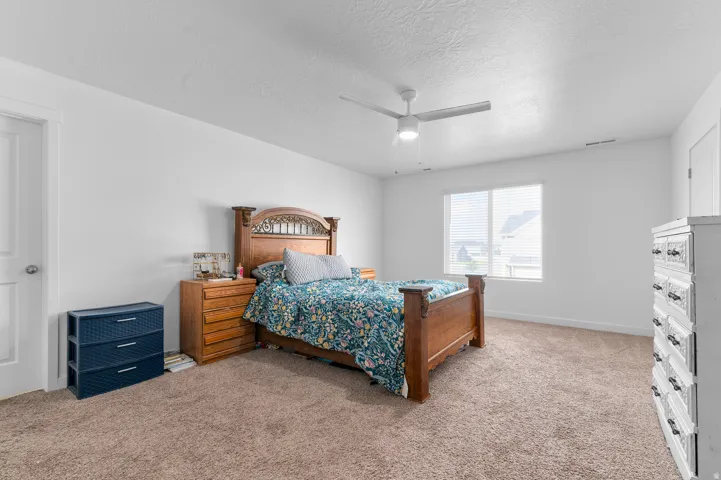 Carpeted flooring, white walls, ceiling fan with light, and a window with blinds