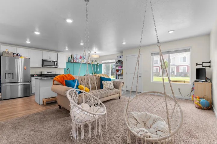Open-concept living space with recessed lighting, wood-finish flooring, and a kitchen featuring white cabinetry and black countertops