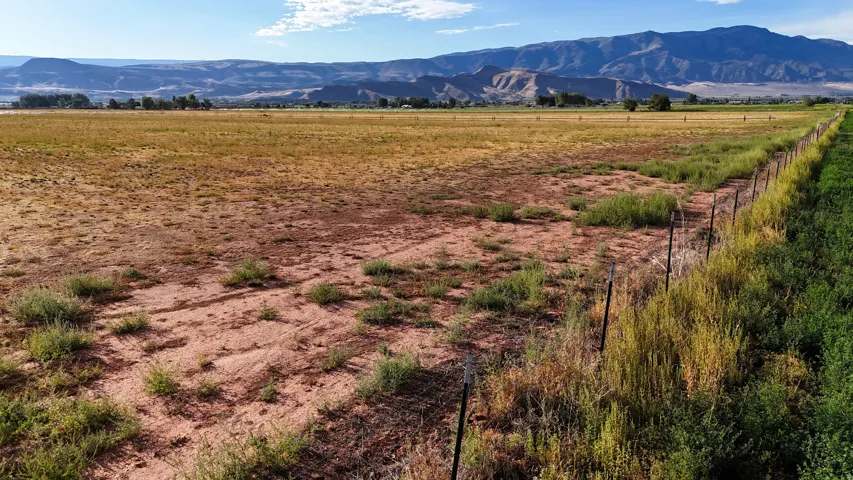 Expansive open land with a partial fence line and distant mountains