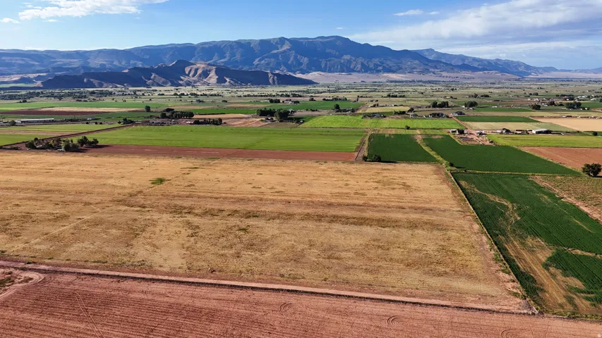 Expansive land parcels with diverse agricultural fields and mountainous backdrop