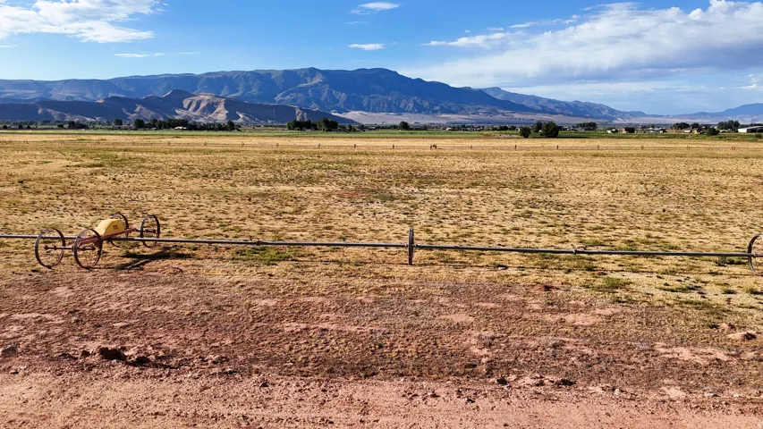 Expansive open fields with distant mountain ranges under a partly cloudy sky
