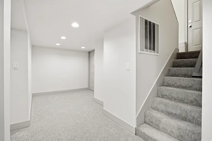 Recessed lighting, light-toned carpeting, and a built-in staircase