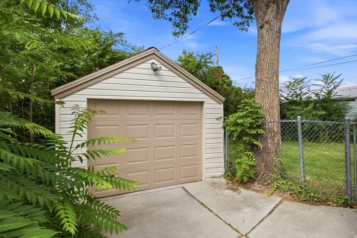 Detached garage with horizontal siding, a gabled roof, and a panel-style garage door