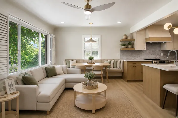 Expansive windows with plantation shutters, wood-finish flooring, a contemporary ceiling fan, and a kitchen featuring a built-in range hood and stone-finish backsplash