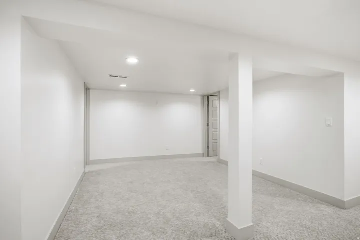 Recessed lighting illuminates the carpeted floor and white walls