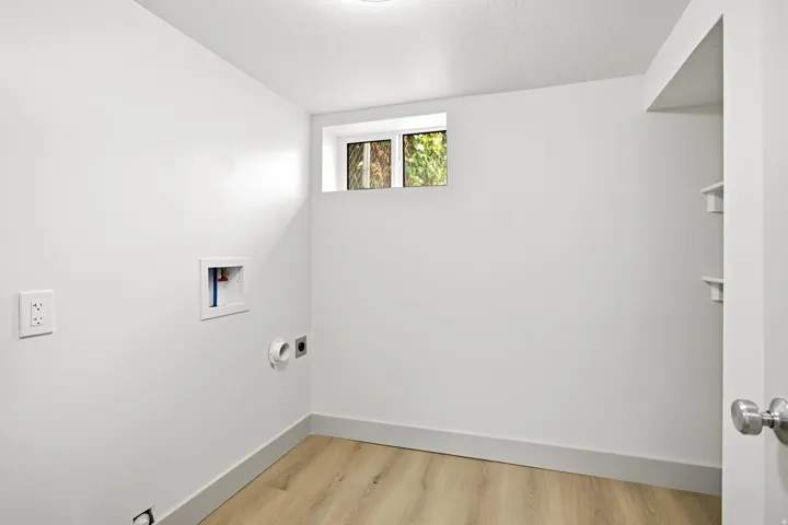 White walls, wood-finish flooring, built-in shelving, and a window