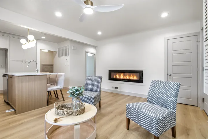 Open-concept living space with wood-finish flooring, a contemporary linear fireplace, and recessed lighting