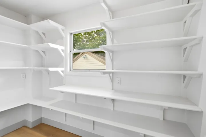 Extensive built-in shelving, natural light from a window, wood-finish flooring