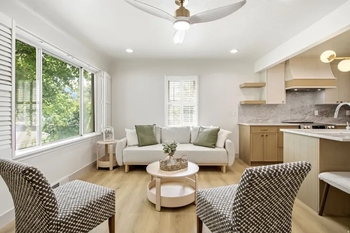 Spacious interior featuring large windows with louvered shutters, wood-finish flooring, a ceiling fan, recessed lighting, and a kitchen with light-toned cabinetry and a built-in range