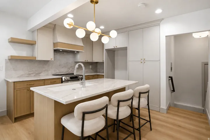 Contemporary kitchen featuring a large central island with an undermount sink, light-toned cabinetry, and wood-finish flooring