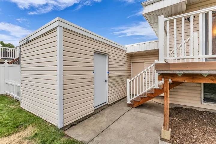 Exterior featuring light-colored siding, a white privacy fence, a concrete patio, and a wood deck with white railings