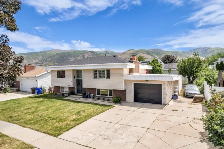 Split-level residence featuring a two-car garage, concrete driveway, and front lawn
