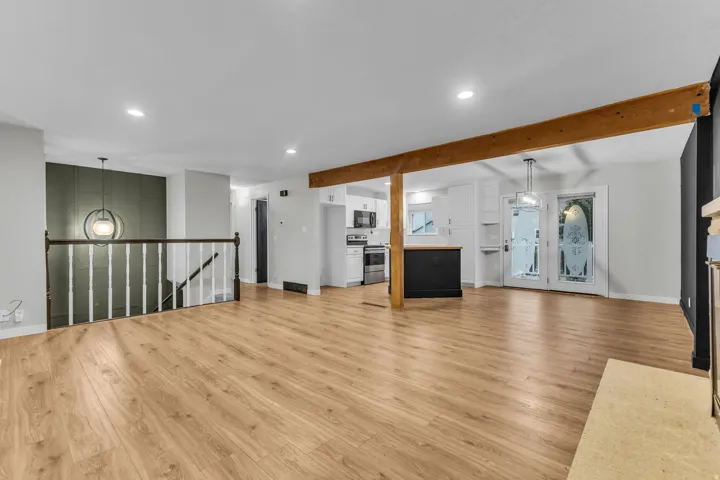Open-concept living area featuring wood-finish flooring, a wood beam, and recessed lighting