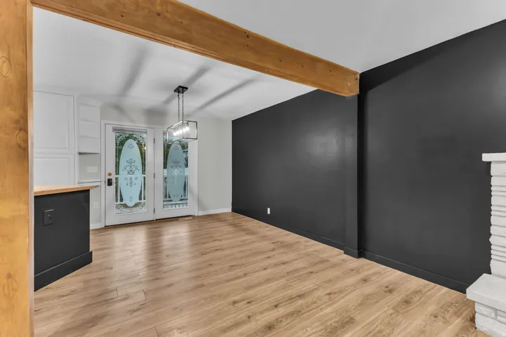 Exposed wood beam, wood-finish flooring, built-in cabinetry, dual glass panel doors, contemporary chandelier