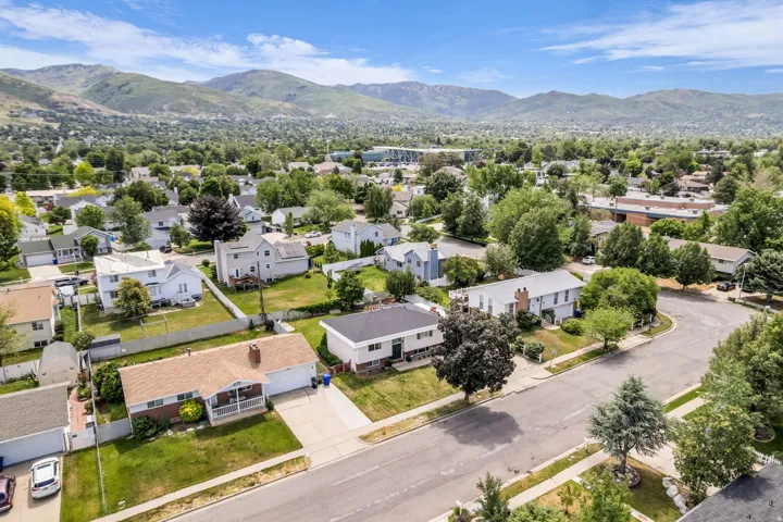 Residential neighborhood with a mountainous backdrop, featuring mature trees and a clear sky
