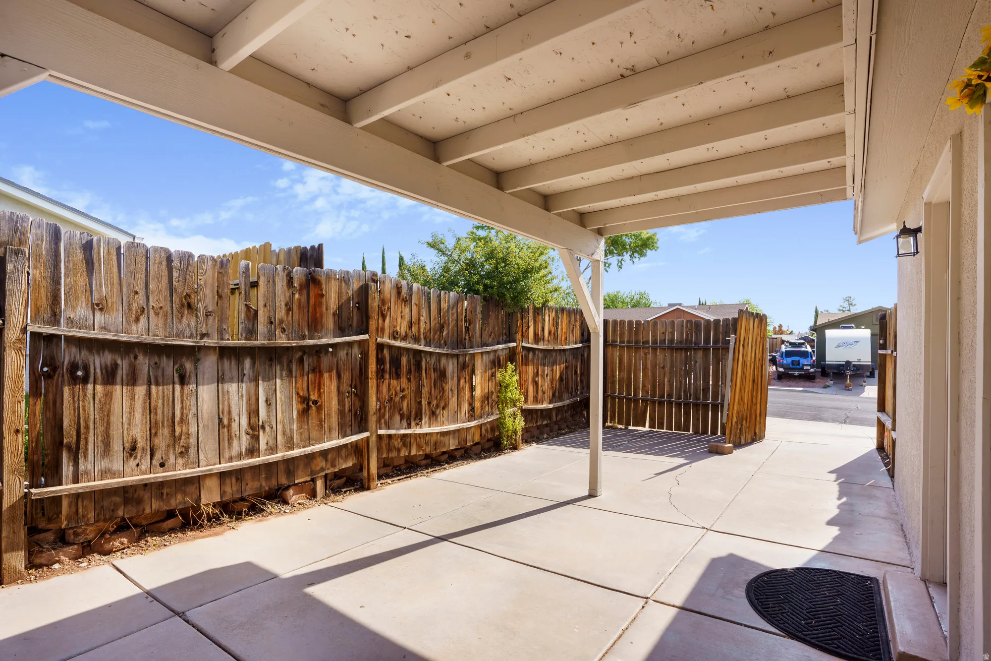Covered patio with a concrete slab, wood privacy fencing, and exterior lighting fixture