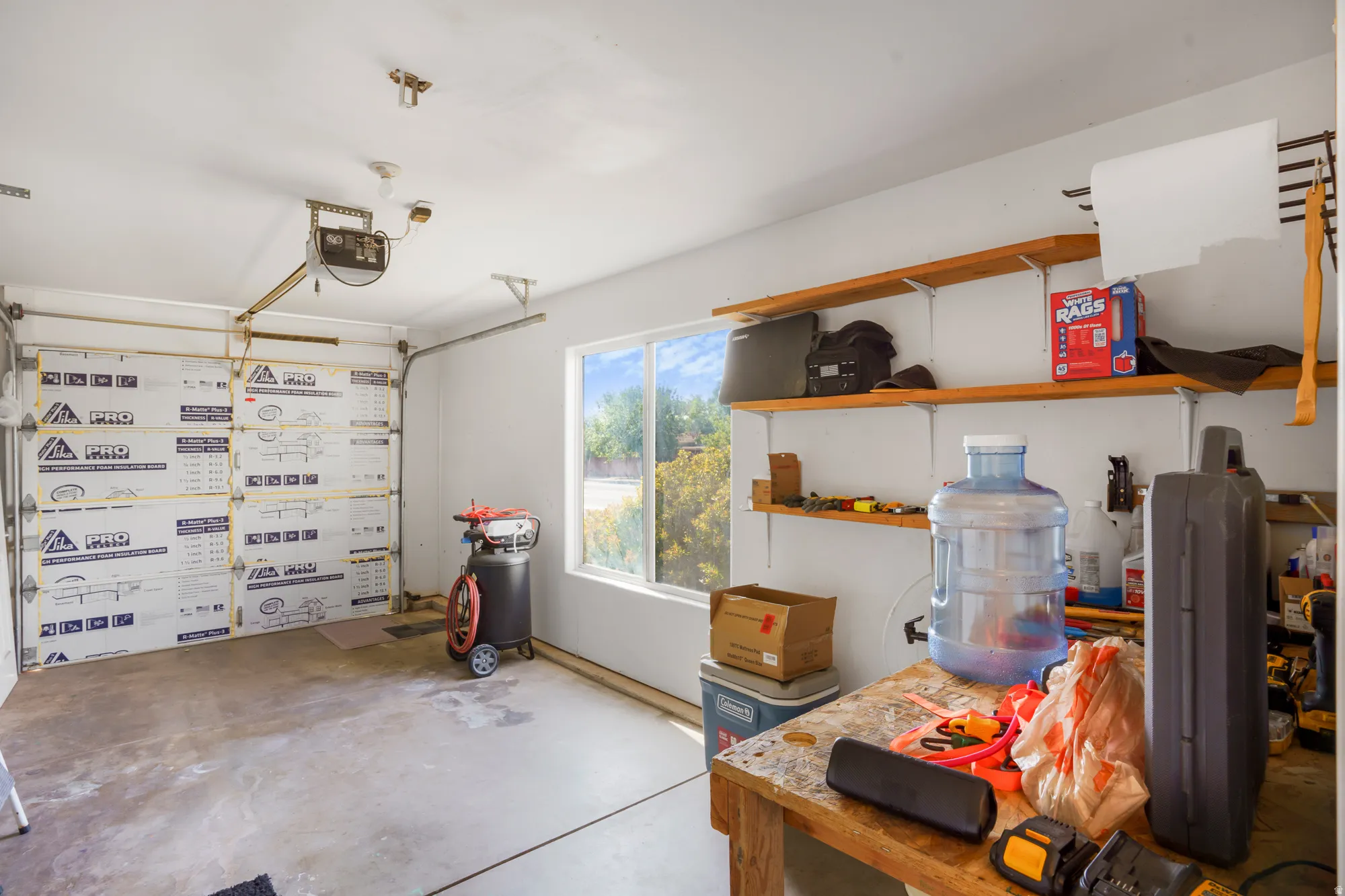 Attached garage featuring a window, built-in shelving, and a garage door opener