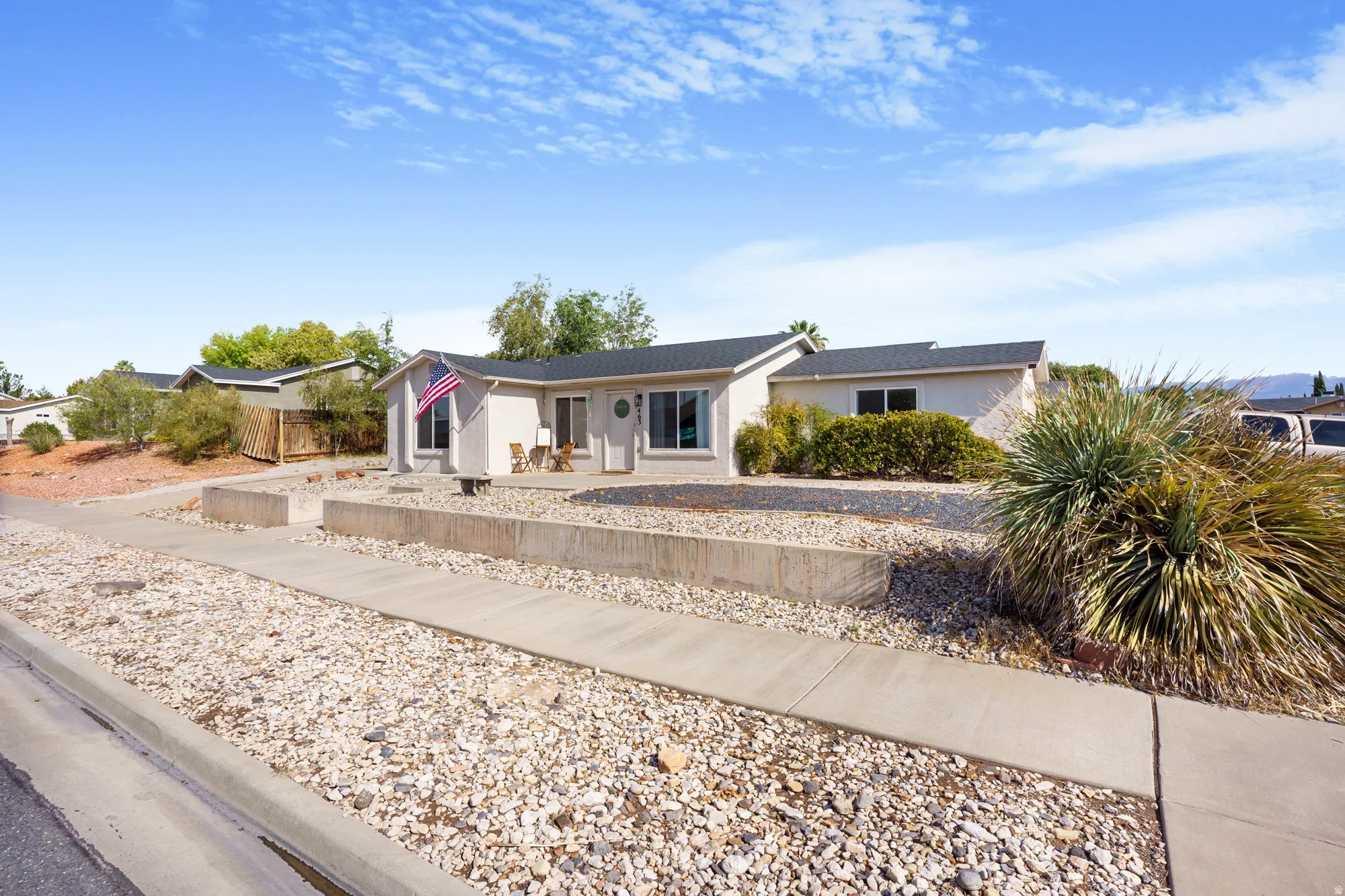 Single-story residence with a light-colored stucco exterior, dark roof, and multiple windows