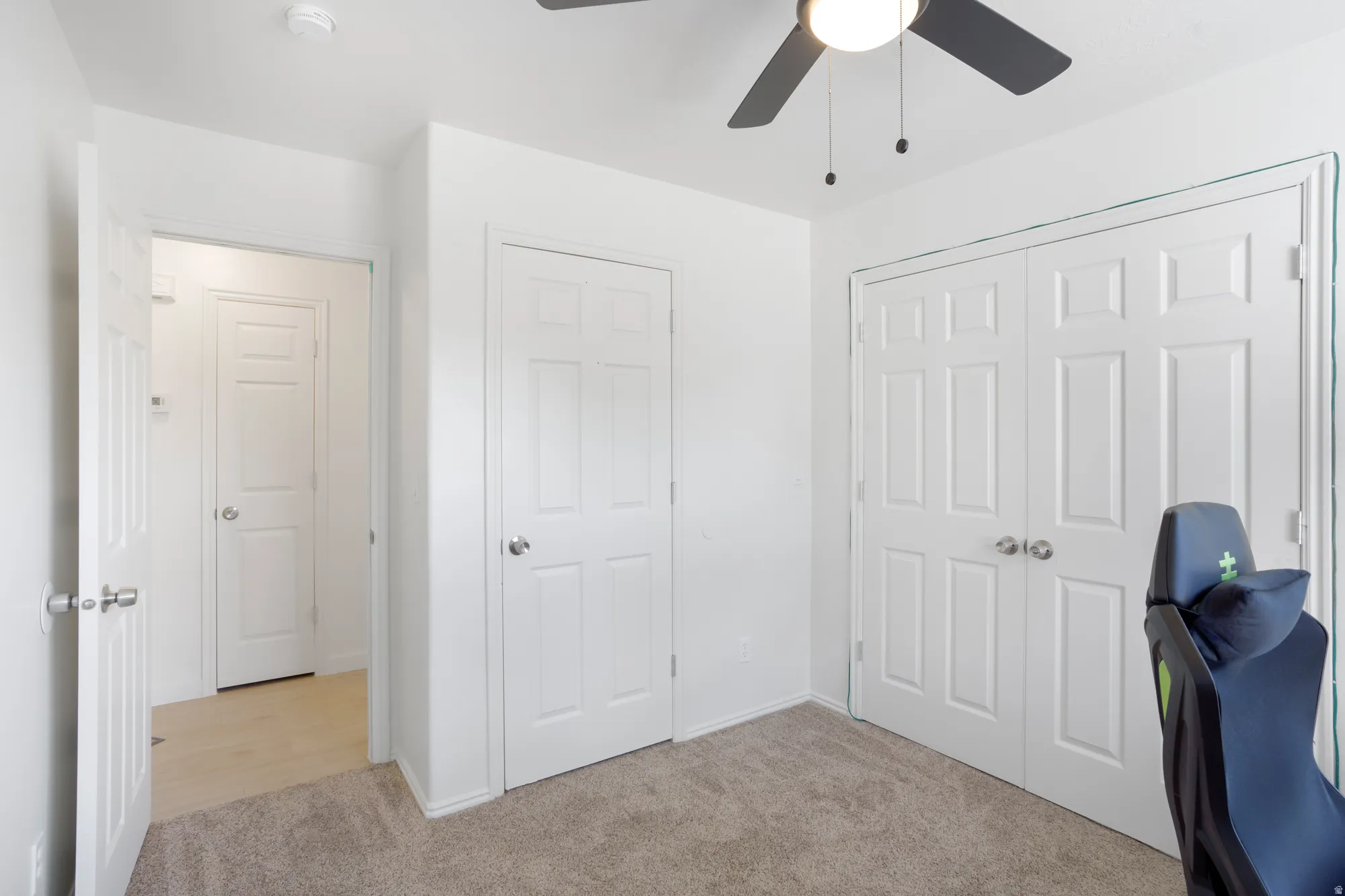 Neutral-toned carpeting with white walls, ceiling fan, and white paneled doors