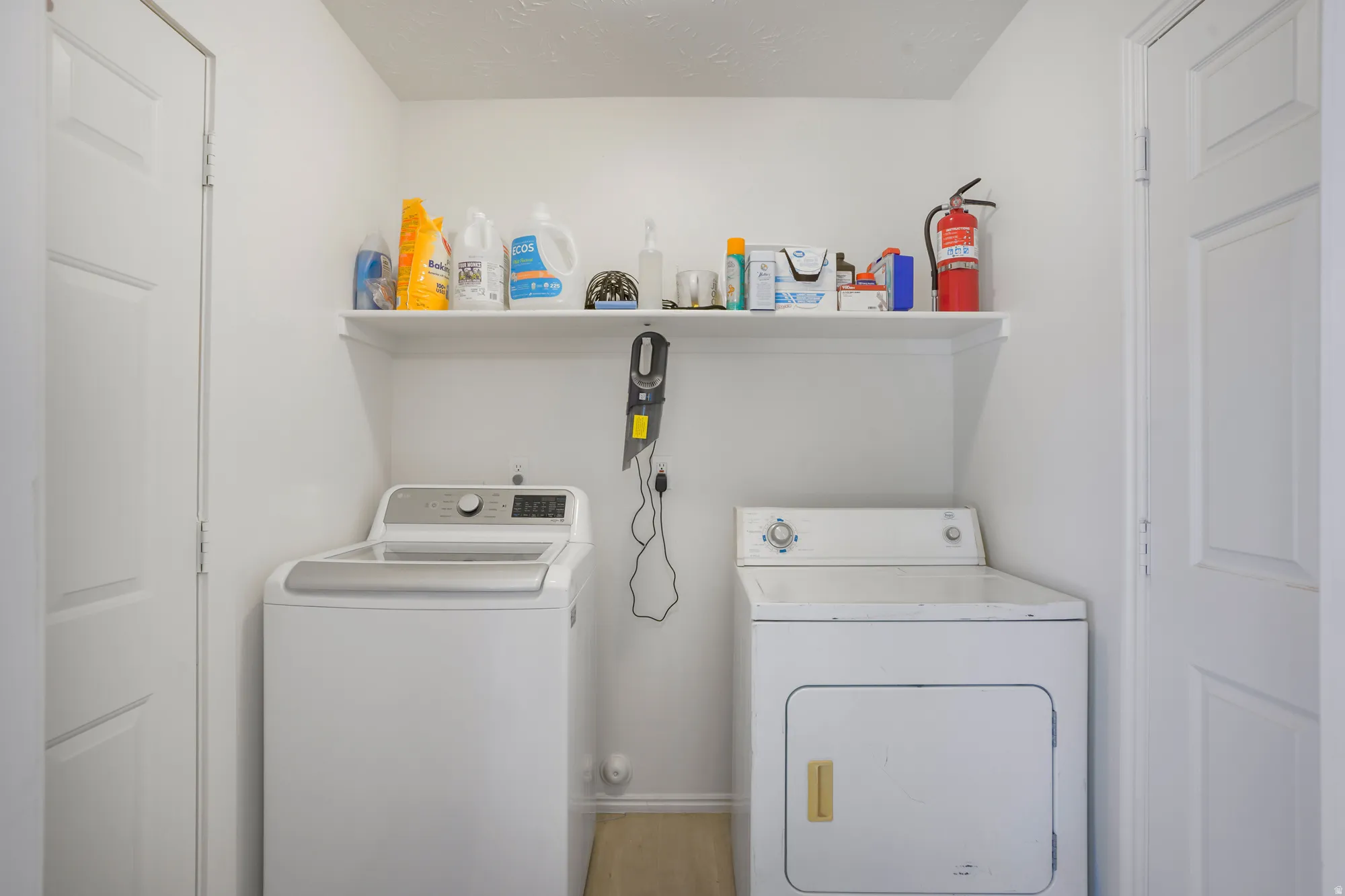Laundry area featuring a built-in shelf and light wood-finish flooring