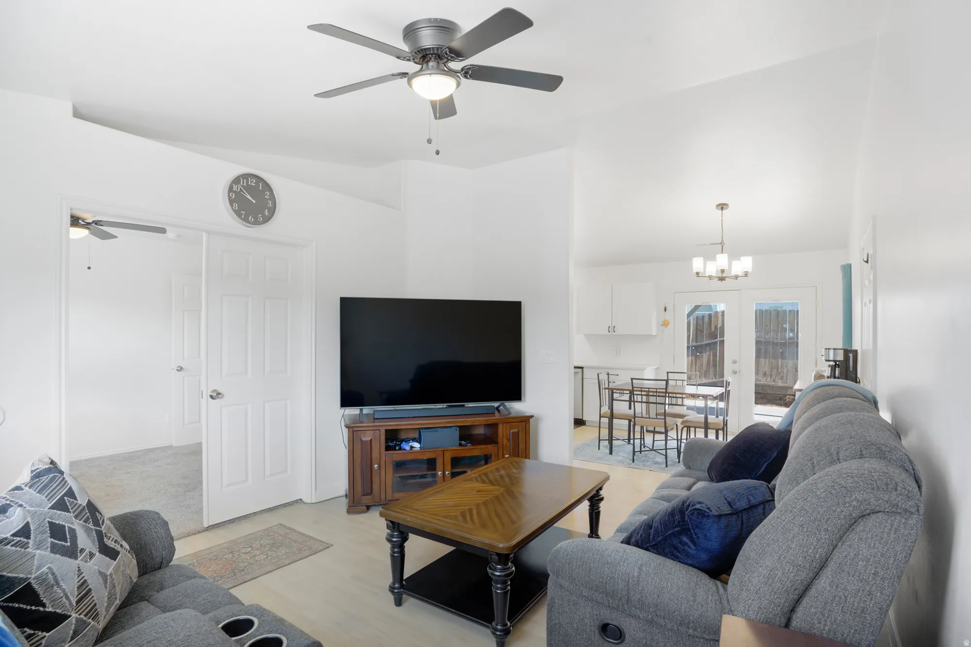 Vaulted ceilings with a ceiling fan, light wood-finish flooring, and white paneled doors