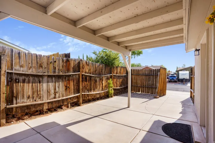 Covered patio with a concrete slab, wood privacy fencing, and exterior lighting fixture