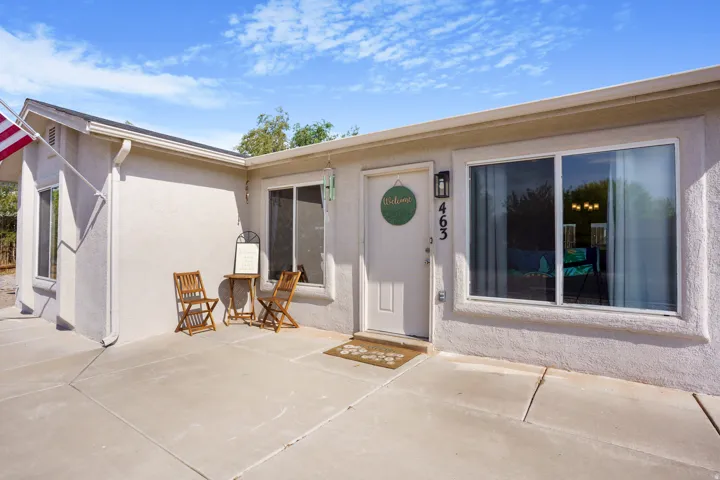 Stucco exterior with a pitched roof, concrete patio, and white-framed windows