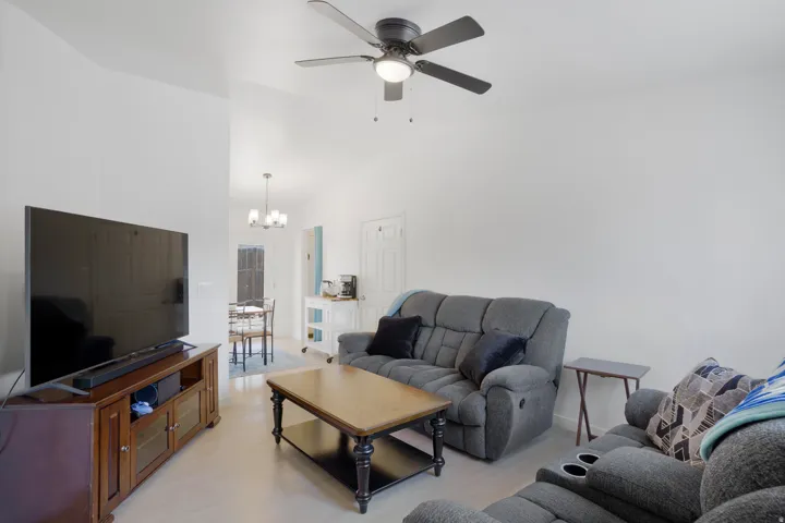 Vaulted ceilings with a ceiling fan, light-toned flooring, and a dining area with a chandelier