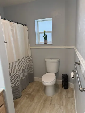 Bathroom featuring a white toilet, tile flooring, and a towel bar