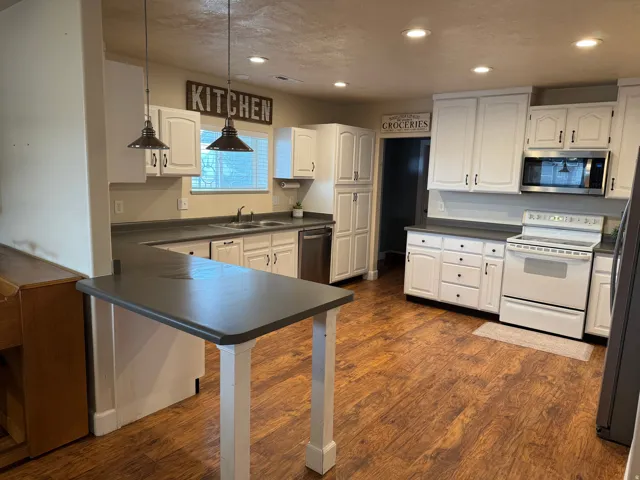 Kitchen featuring white cabinetry, wood-finish flooring, recessed lighting, and a stainless steel microwave