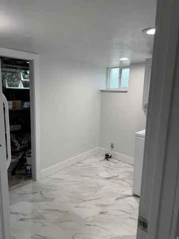 White walls with recessed lighting, marble-look tile flooring, and a small window