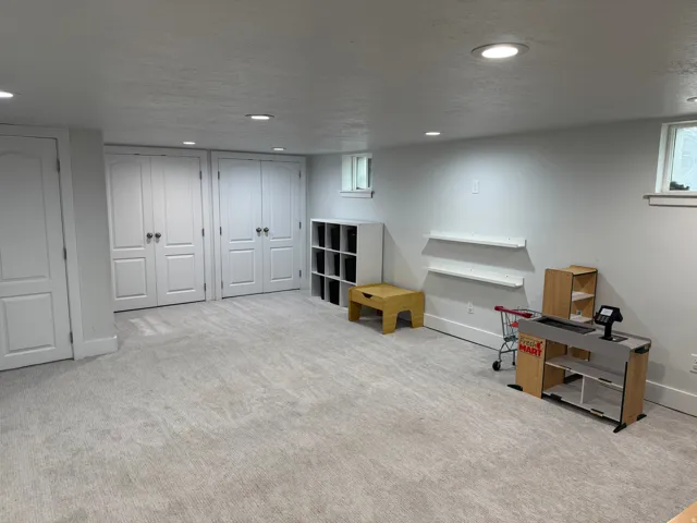 Recessed lighting illumination, light-toned carpeting, white walls, and built-in closet doors with dark hardware