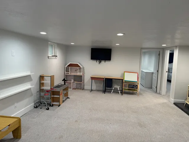 Recessed lighting illuminates a carpeted open area with white walls