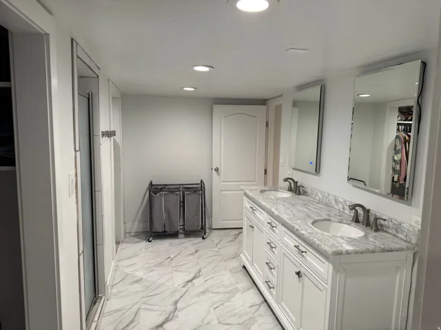 Dual vanity with white cabinetry and a stone countertop
