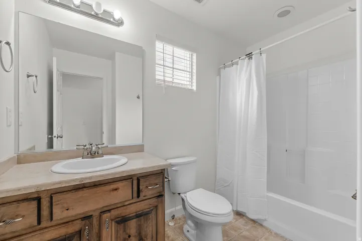 Full bathroom featuring a wood-finish vanity with an integrated sink, polished chrome faucet, and a combination shower/tub