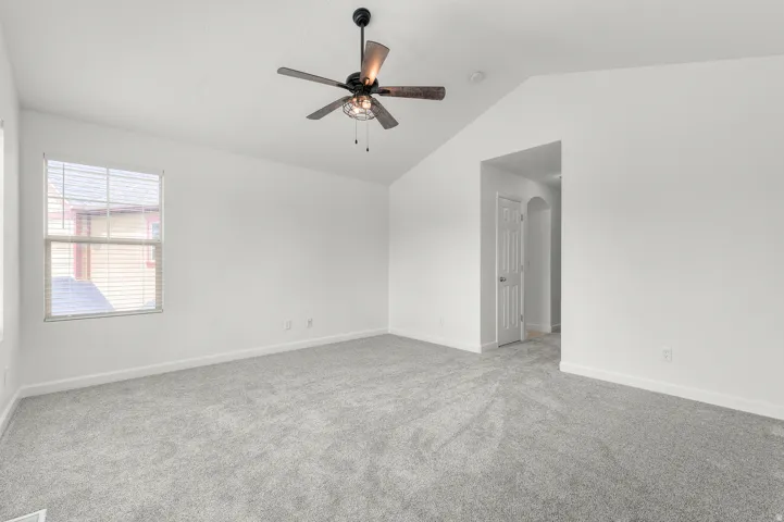 Vaulted ceiling with a ceiling fan, neutral wall paint, window with blinds, and light grey carpeting